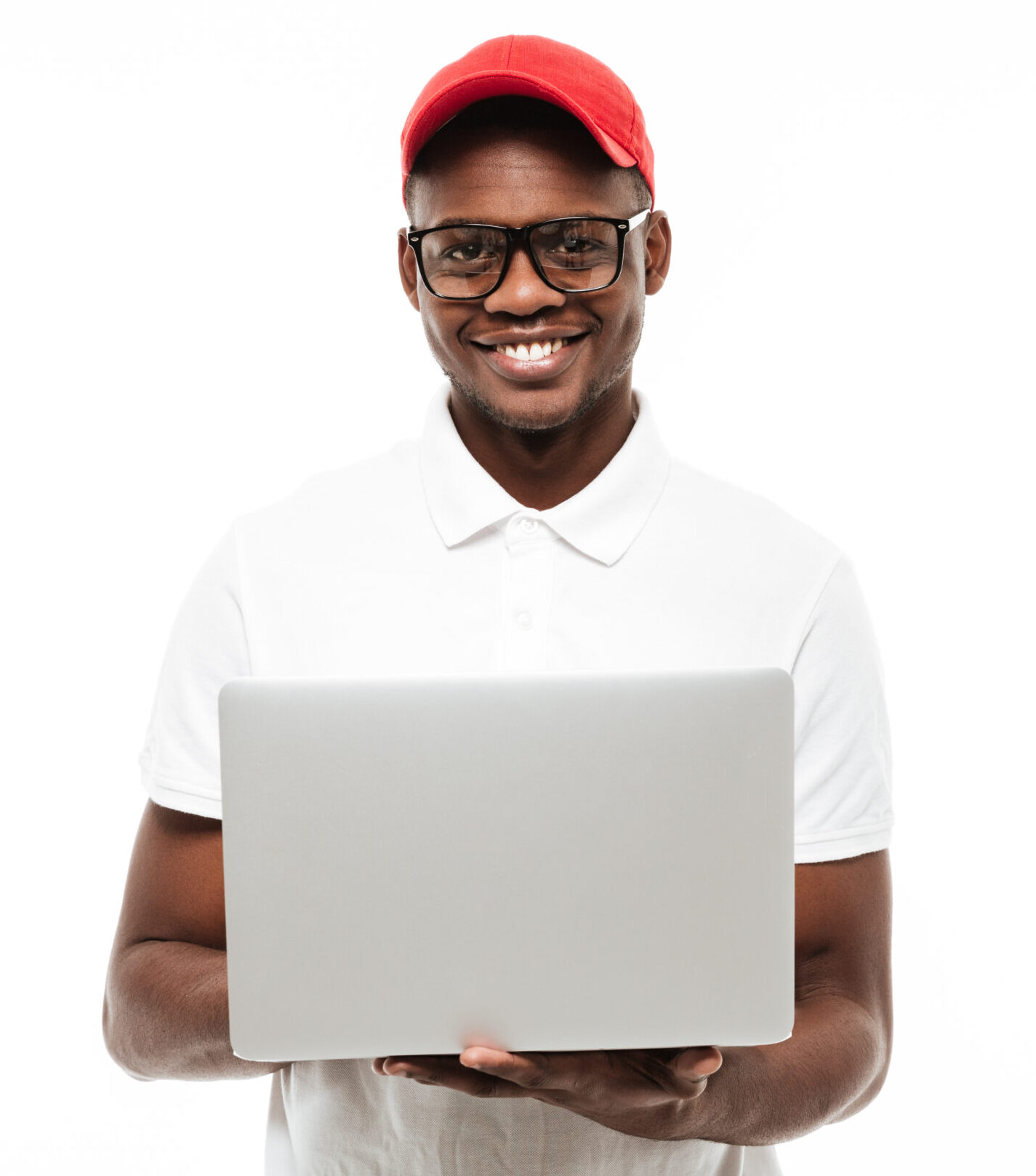 Photo of cheerful young african man wearing cap isolated over white background using laptop computer. Looking at camera.